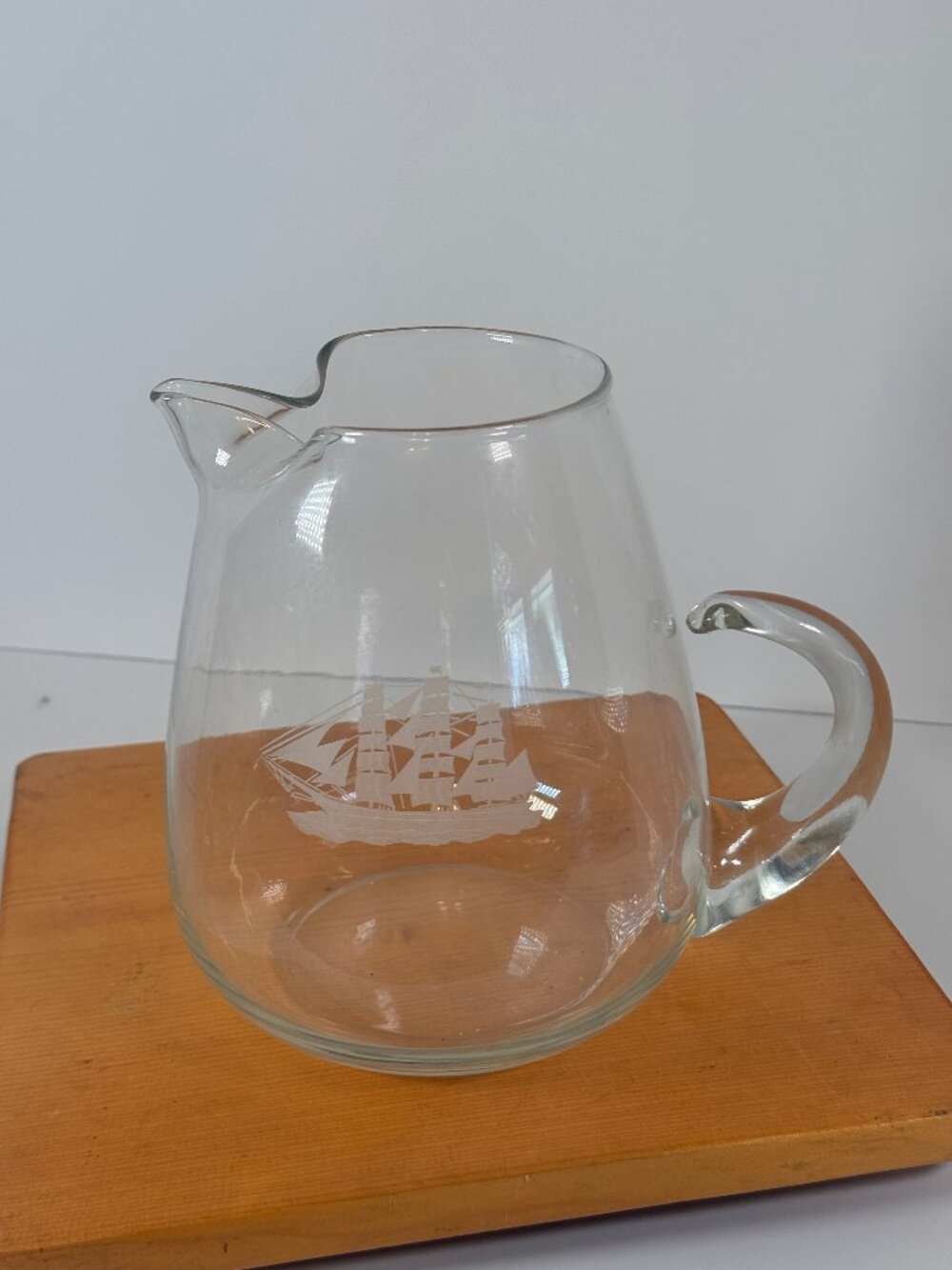 Vintage clear glass hand blown pitcher with applied handle and pinched spout.